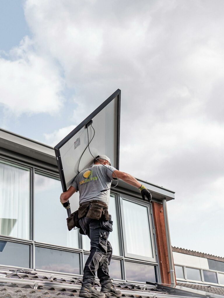 A worker installs a solar panel on a residential rooftop emphasizing renewable energy.