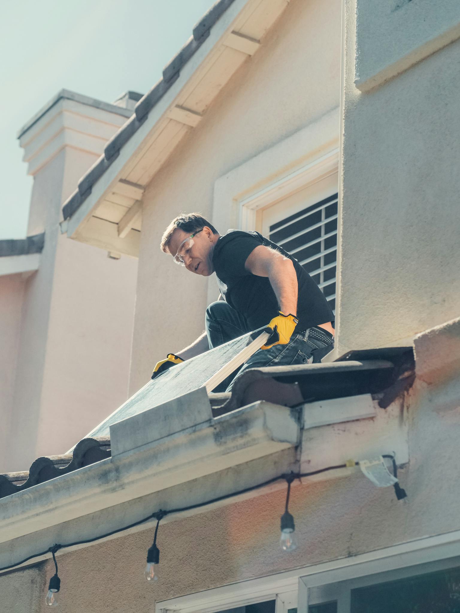 A worker is installing solar panels on a residential rooftop, promoting clean energy.